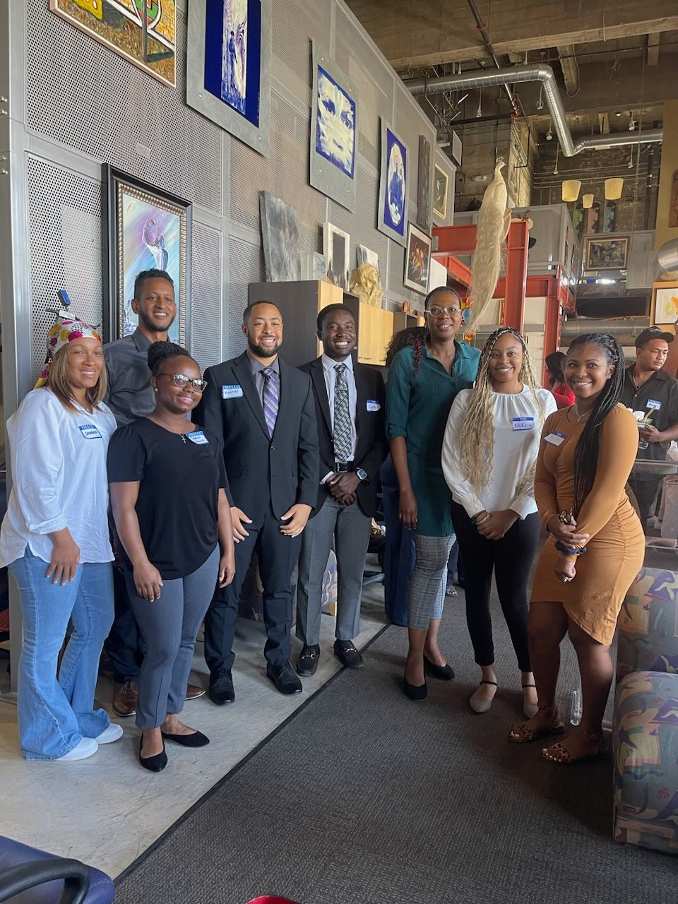 Group of people posing together indoors beside a brick wall and carpeted walkway at Auxiliary to the Sinkler Miller Medical Association