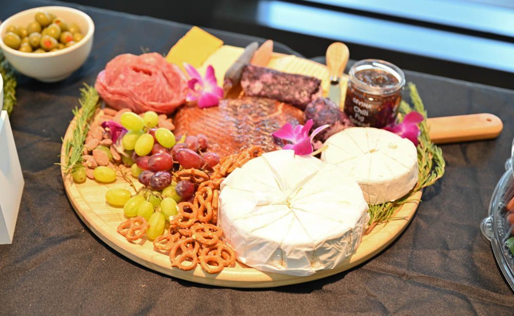 Charcuterie board with sliced cheese, cured meats, grapes, olives, crackers, and jam on a dark table