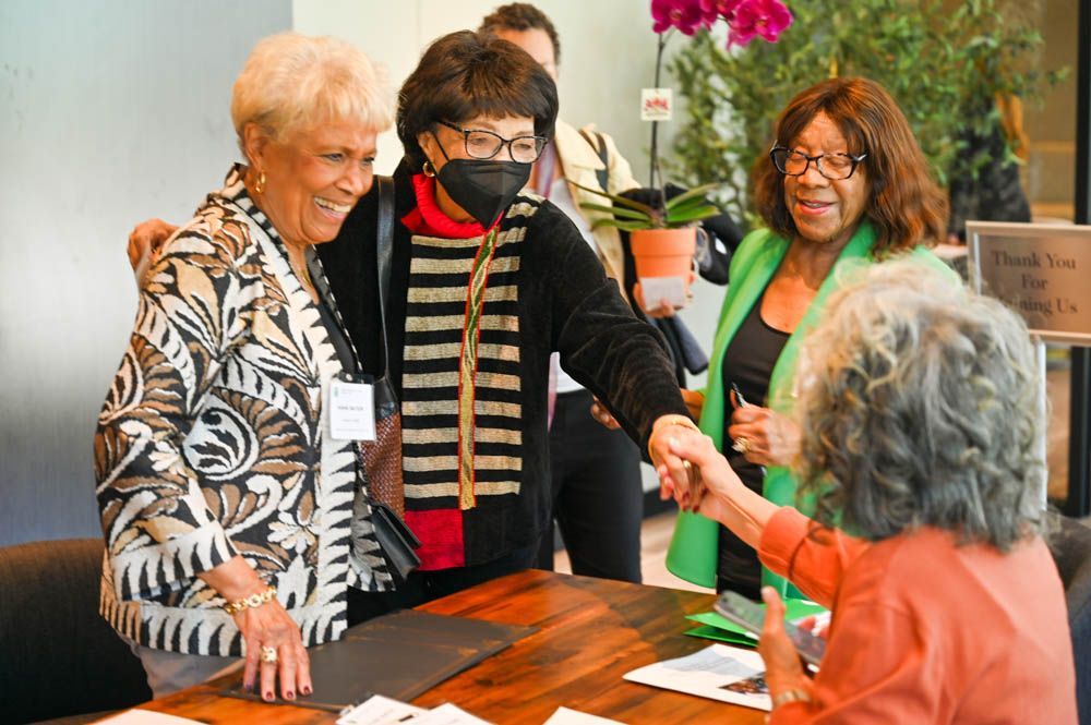 People greeting at a registration table in a bright indoor event space