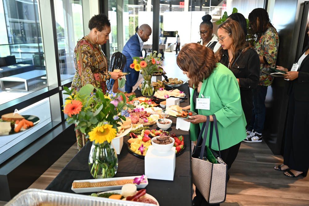 People gathered around a buffet table in an office lobby, serving food and drinks.