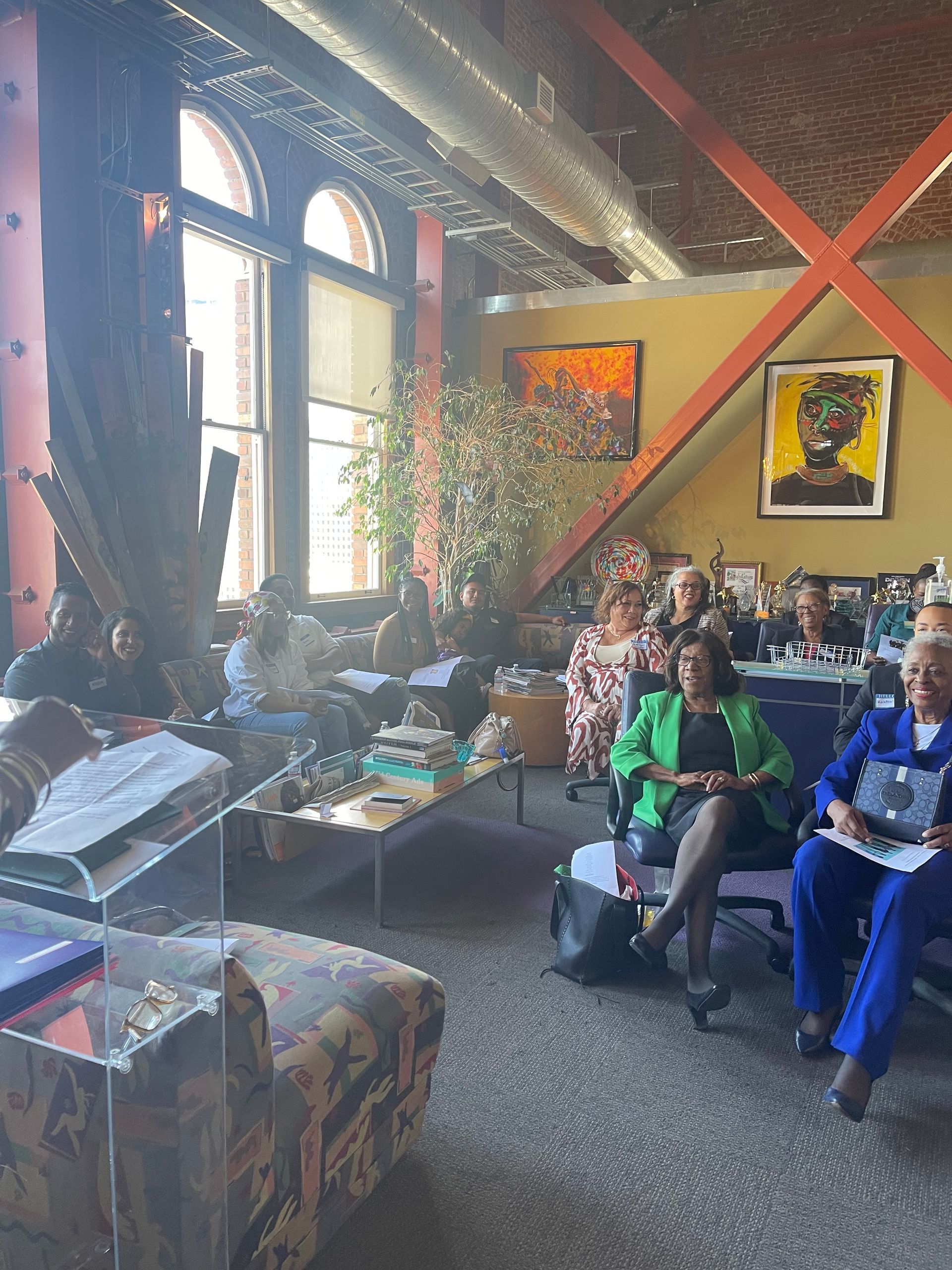 People seated in a cozy lounge with high windows, colorful walls, and decorative art.