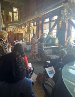 People seated in a cozy room listening to a speaker near the front windows at Auxiliary to the Sinkler Miller Medical Association