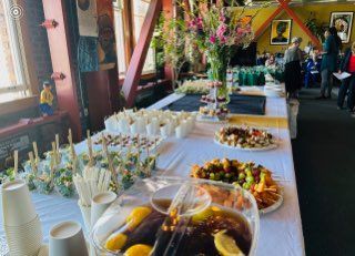 Buffet table with assorted pastries and appetizers at an indoor event, decorated with flowers