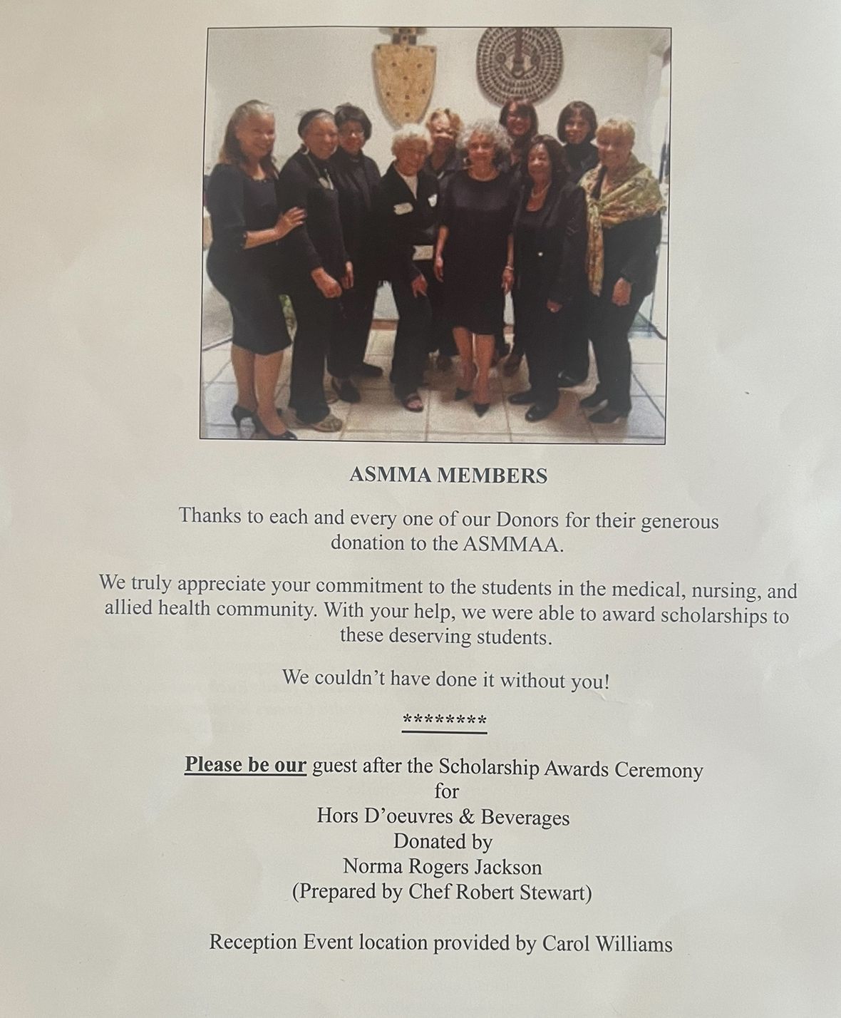 Group of people posing indoors at a memorial service with flowers and tribute text below.