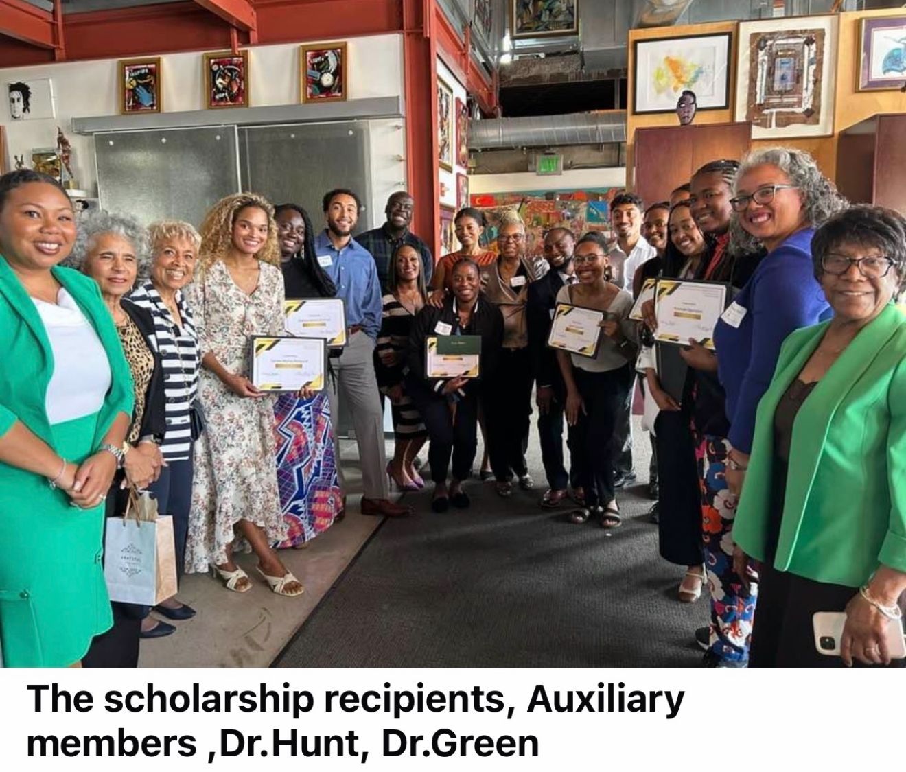 Scholars and Auxiliary members posing indoors, holding certificates in a group photo.