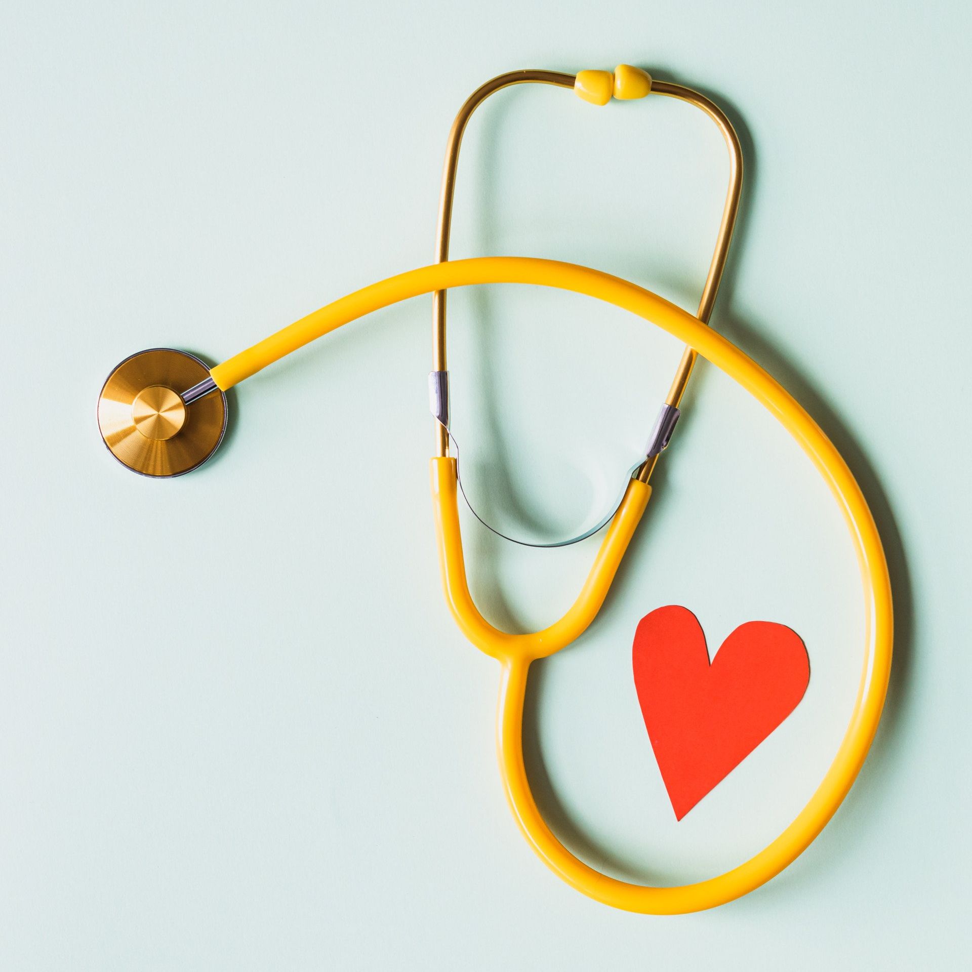 Yellow stethoscope with a red heart icon on a light background