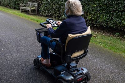 Woman driving a mobility scooter on a paved path