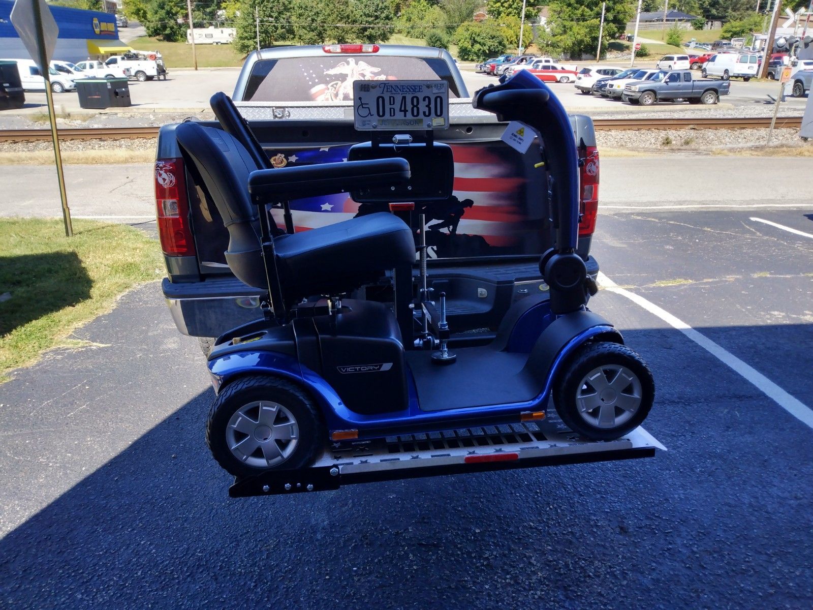 Blue mobility scooter loaded in the back of a pickup truck in a parking lot