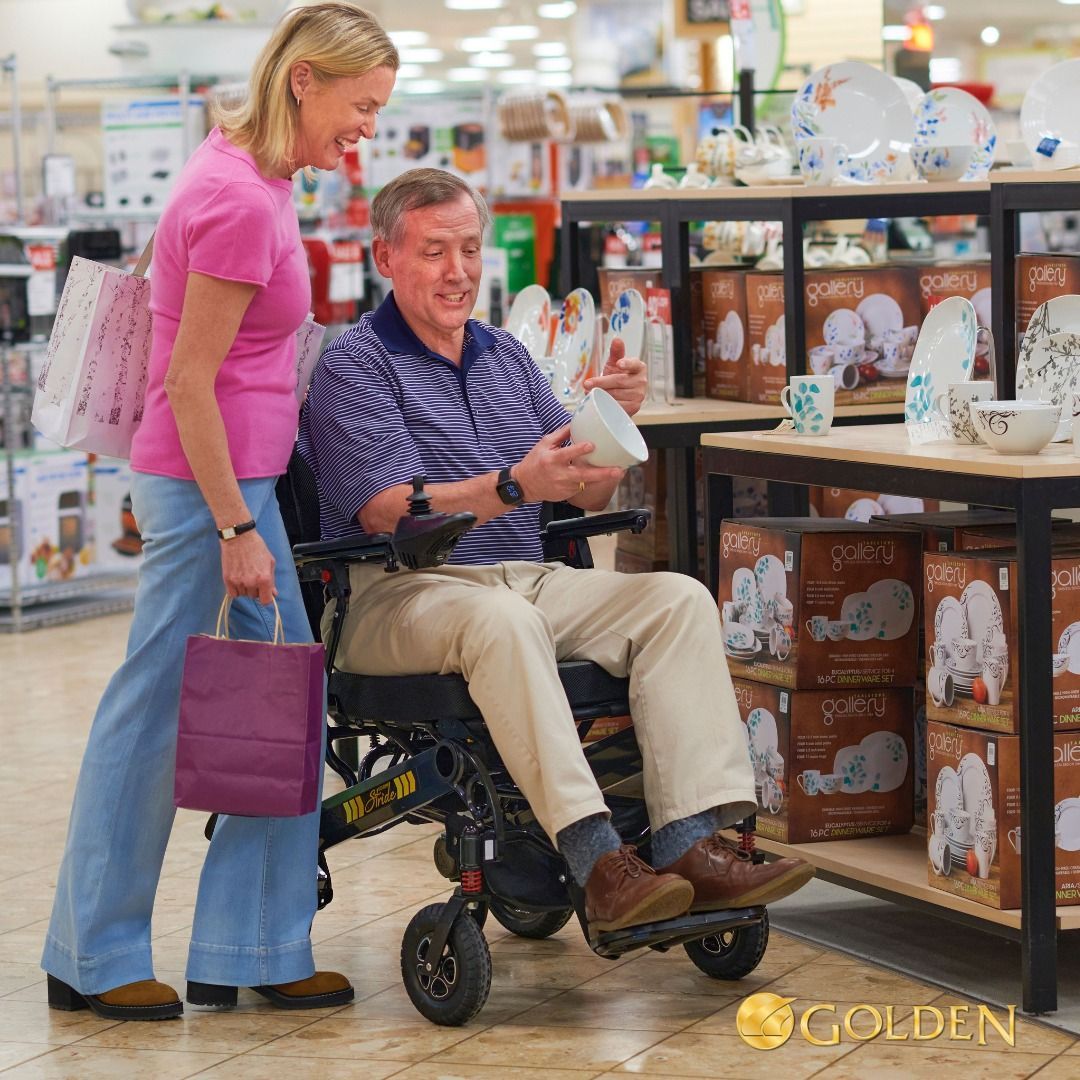 Woman assisting man in wheelchair choosing dishes in a home goods store