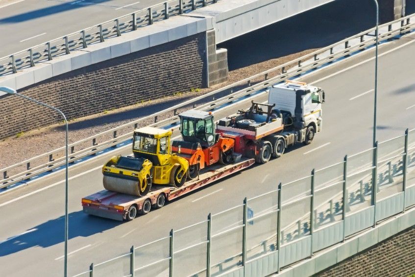 An Aerial View of a Truck Carrying Construction Equipment on a Highway — JEC Transport in Winnellie, NT