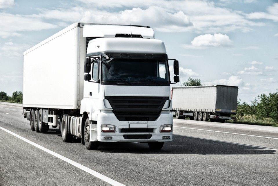 A White Semi Truck is Driving Down a Highway — JEC Transport in Winnellie, NT