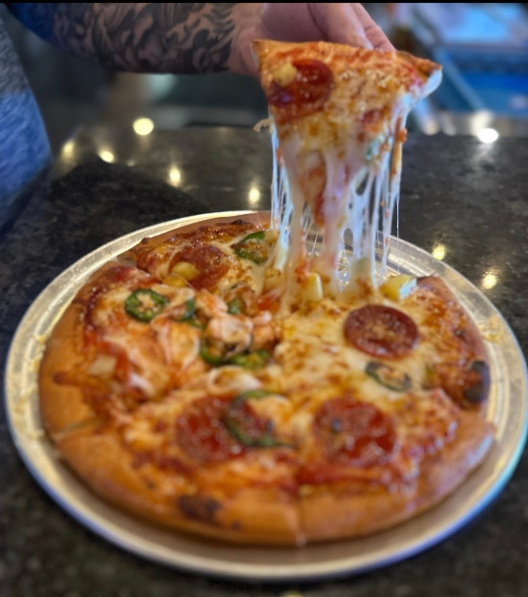 A person is taking a slice of pepperoni pizza