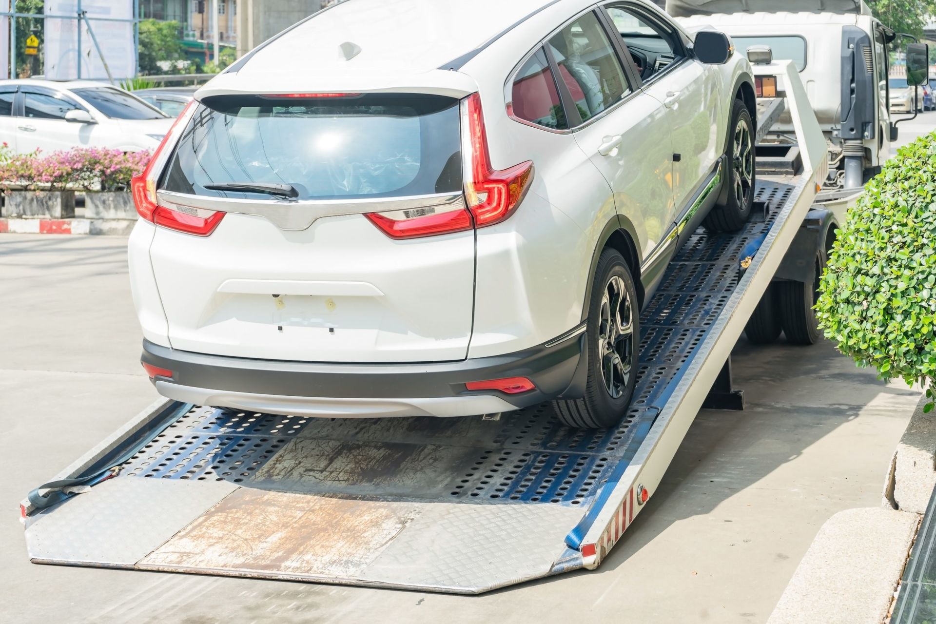 VUS blanc en cours de chargement sur la rampe inclin&eacute;e d&rsquo;une d&eacute;panneuse &agrave; plateau.