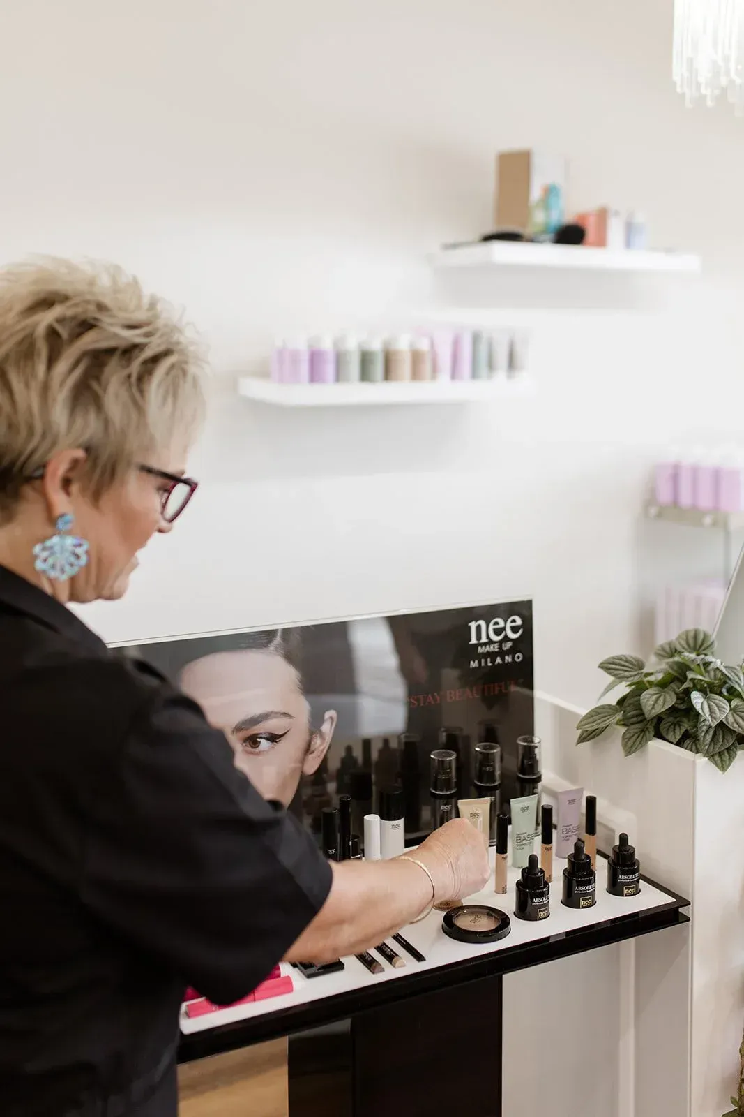 Woman Browsing Beauty Products on a Display Shelf in a Bright Salon — Hair Truss & Co In Wallsend, NSW