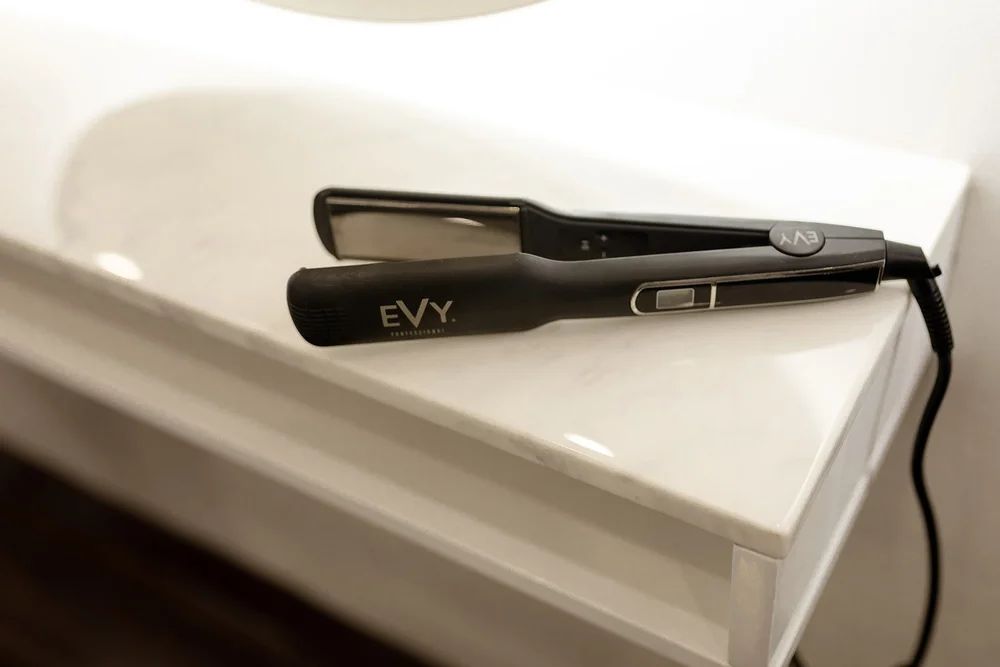 Black Hair Straightener on a White Surface With Cord Attached — Hair Truss & Co In Wallsend, NSW