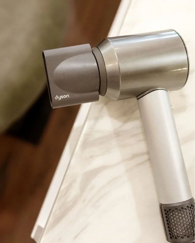 Black and Silver Hair Dryer Resting on a Marble Countertop — Hair Truss & Co In Wallsend, NSW
