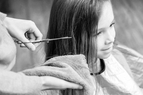 Hairdresser cutting a young client’s hair with scissors — Hair Truss & Co In Wallsend, NSW