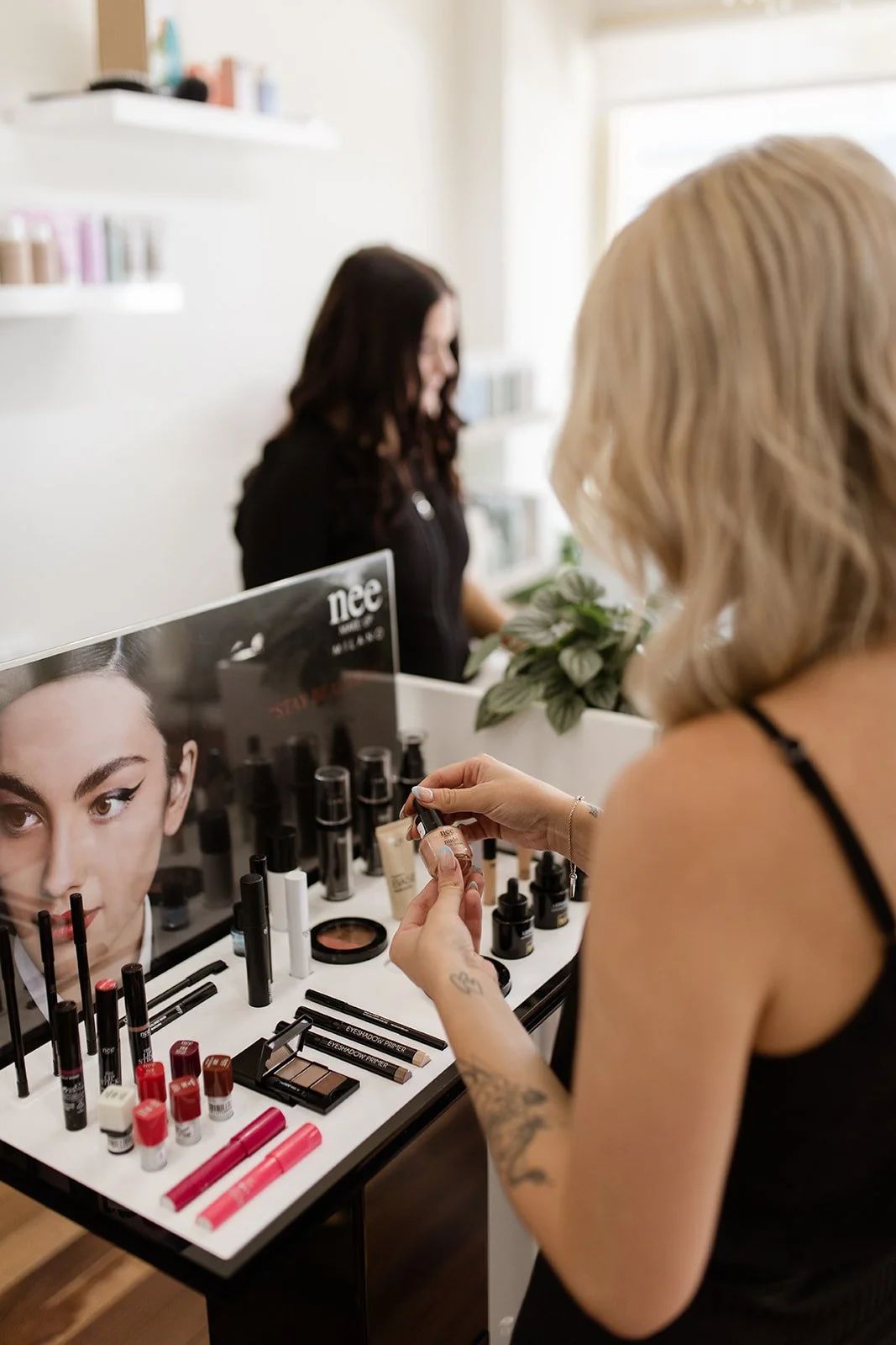Woman Applying Makeup at a Vanity With Cosmetics — Hair Truss & Co In Wallsend, NSW