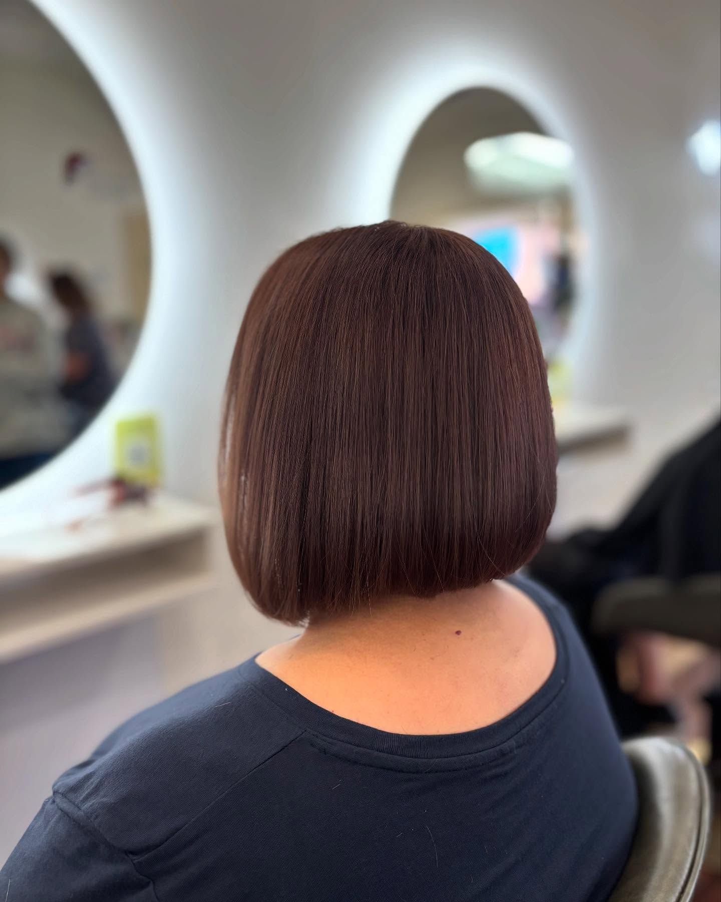 Stylist Trimming a Seated Client’s Long Blonde Hair in a Bright Salon — Hair Truss & Co In Wallsend, NSW