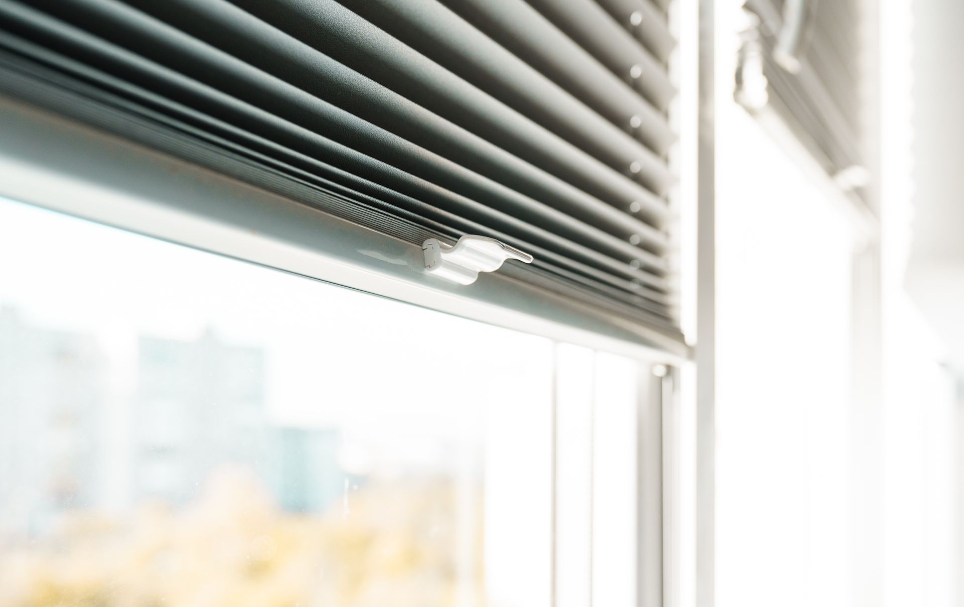 Close-up of horizontal window blinds partially lowered on a sunlit window. Close-up of horizontal window blinds partially lowered on a sunlit window.