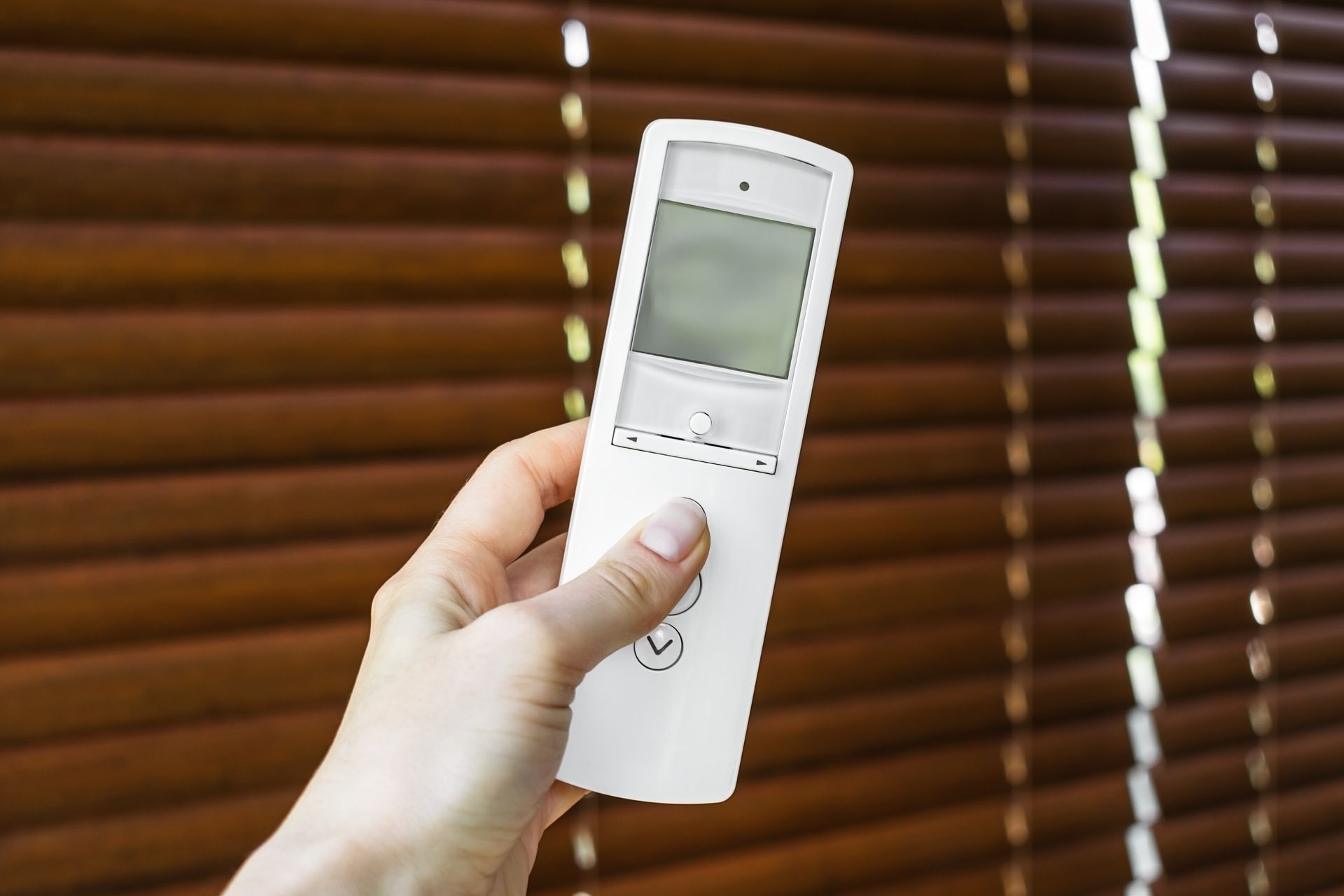 A woman is using a control for the motorized blinds. A woman is using a control for the motorized blinds.