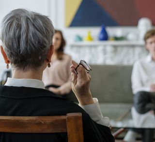 A woman sitting in a chair holding a pair of glasses