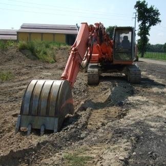 Escavatore Hitachi arancione su una strada sterrata, con braccio teso