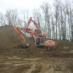 Escavatore Hitachi arancione su una strada sterrata, con braccio teso