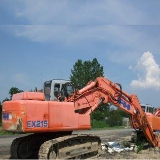 Escavatore Hitachi arancione su una strada sterrata, con braccio teso