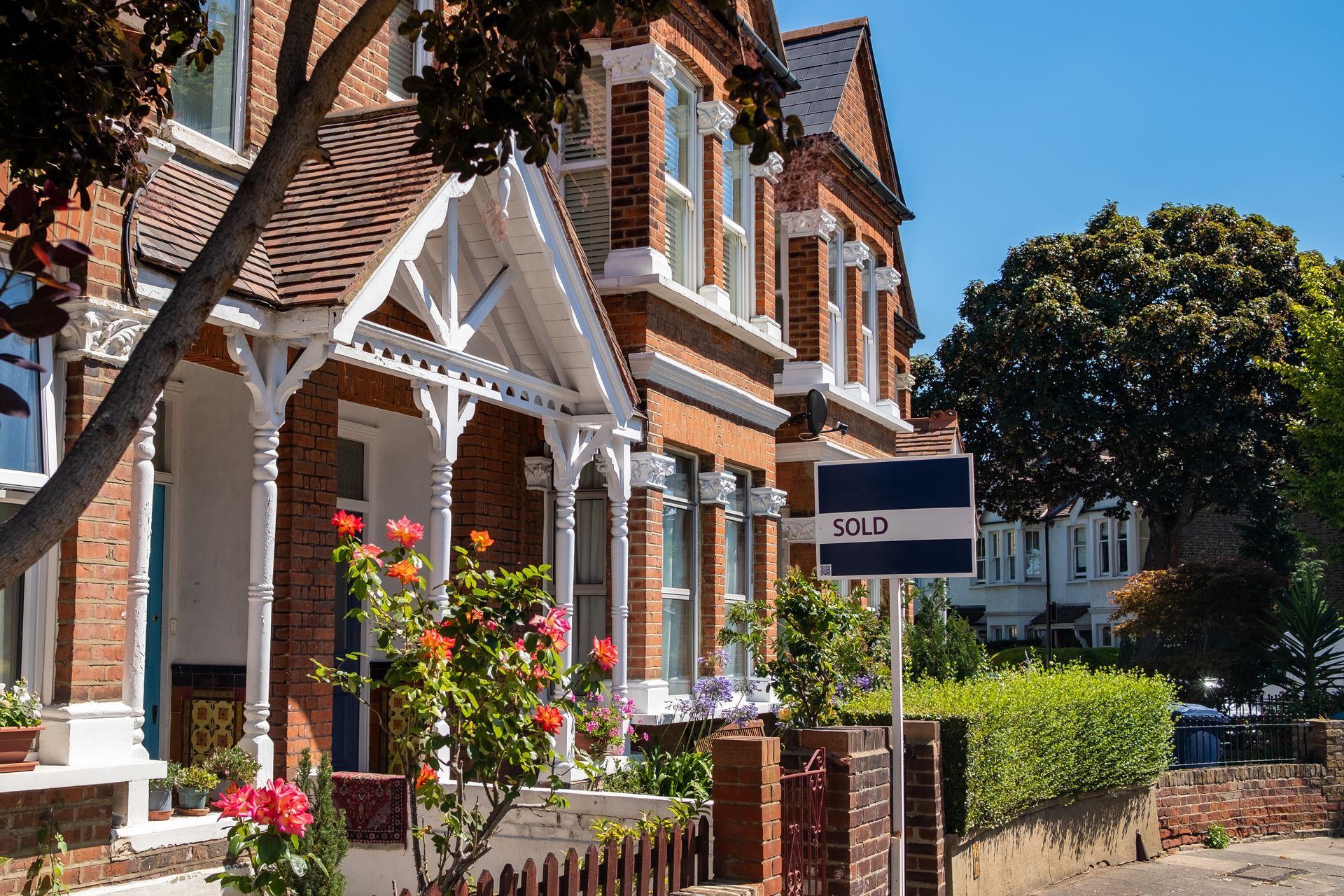 Brick row houses with white trim and flower boxes along a sunny street