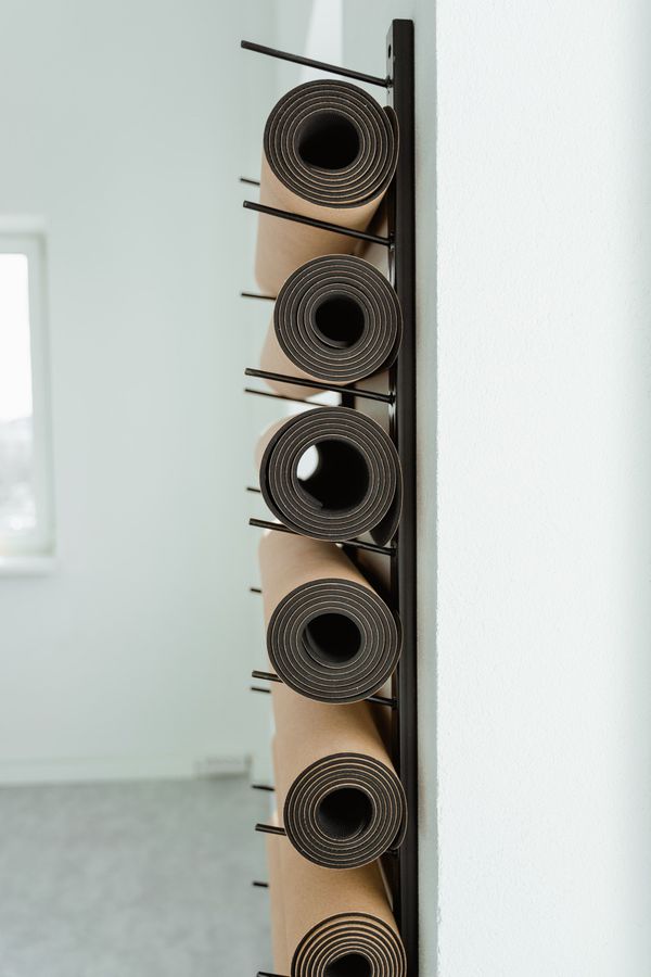 yoga mats rolled and sitting on basic shelves on a wall