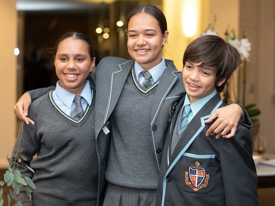 Two girls and one boy from Yalari's scholarship program wearing boarding school uniforms and smiling at the camera.