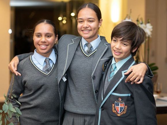 Two girls and one boy from Yalari's scholarship program wearing boarding school uniforms and smiling at the camera.