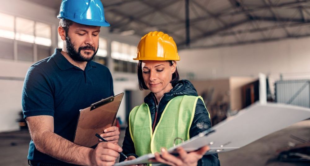 A man and a woman are looking at a clipboard in a warehouse.