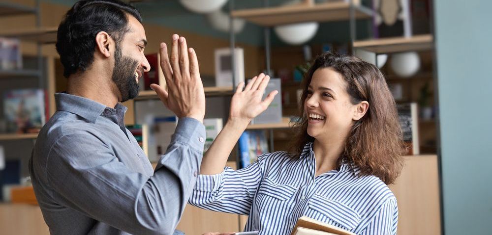 A man and a woman are giving each other a high five.