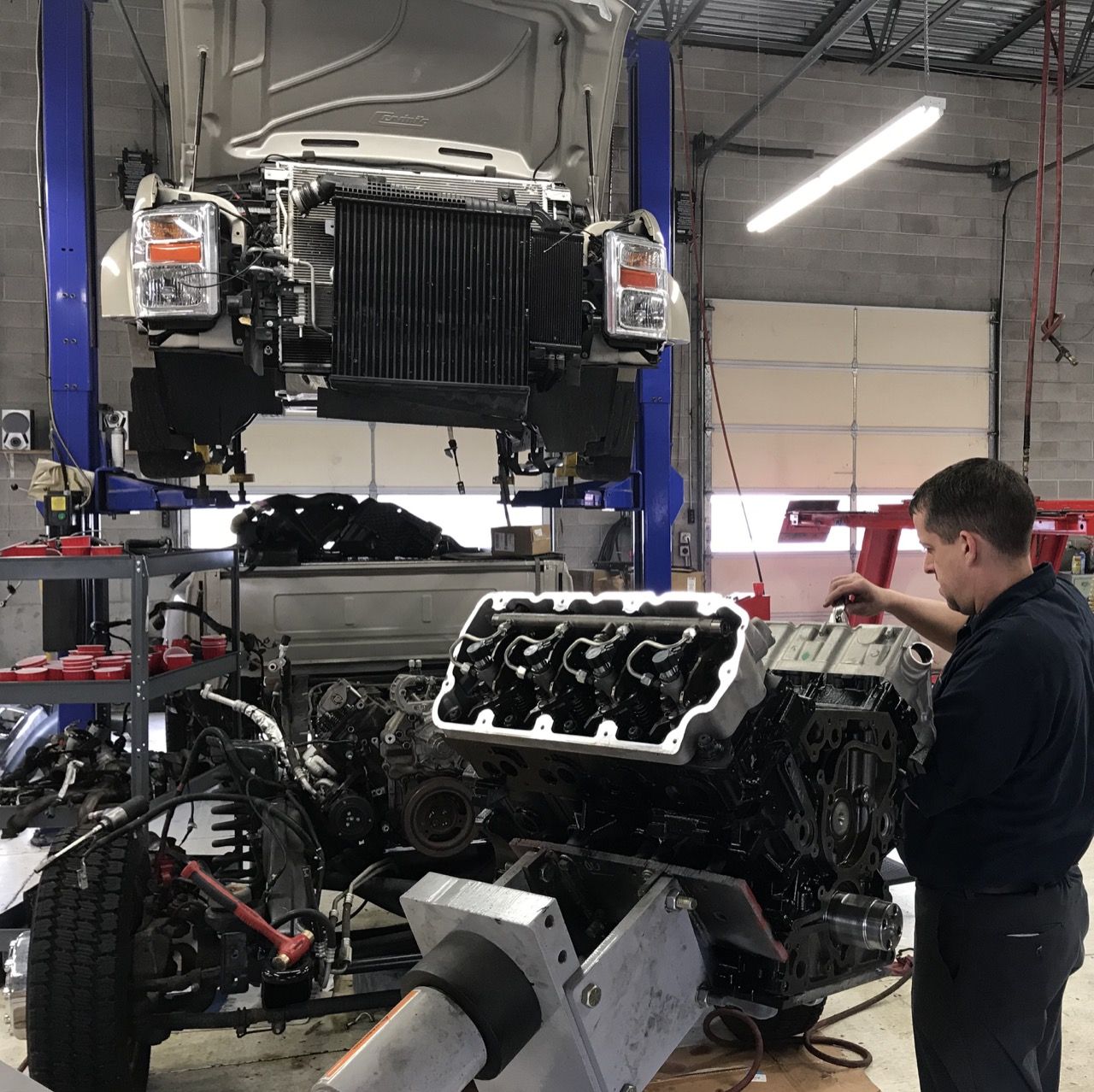 Mechanic working on a truck engine in a repair shop; the engine is disassembled. | Don's D.I. Auto & Truck Service