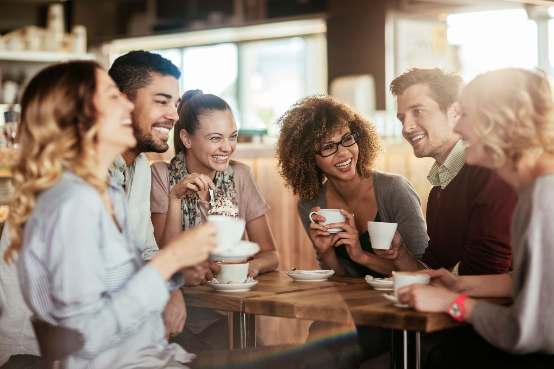 Group of friends smiling and drinking coffee in a cafe.