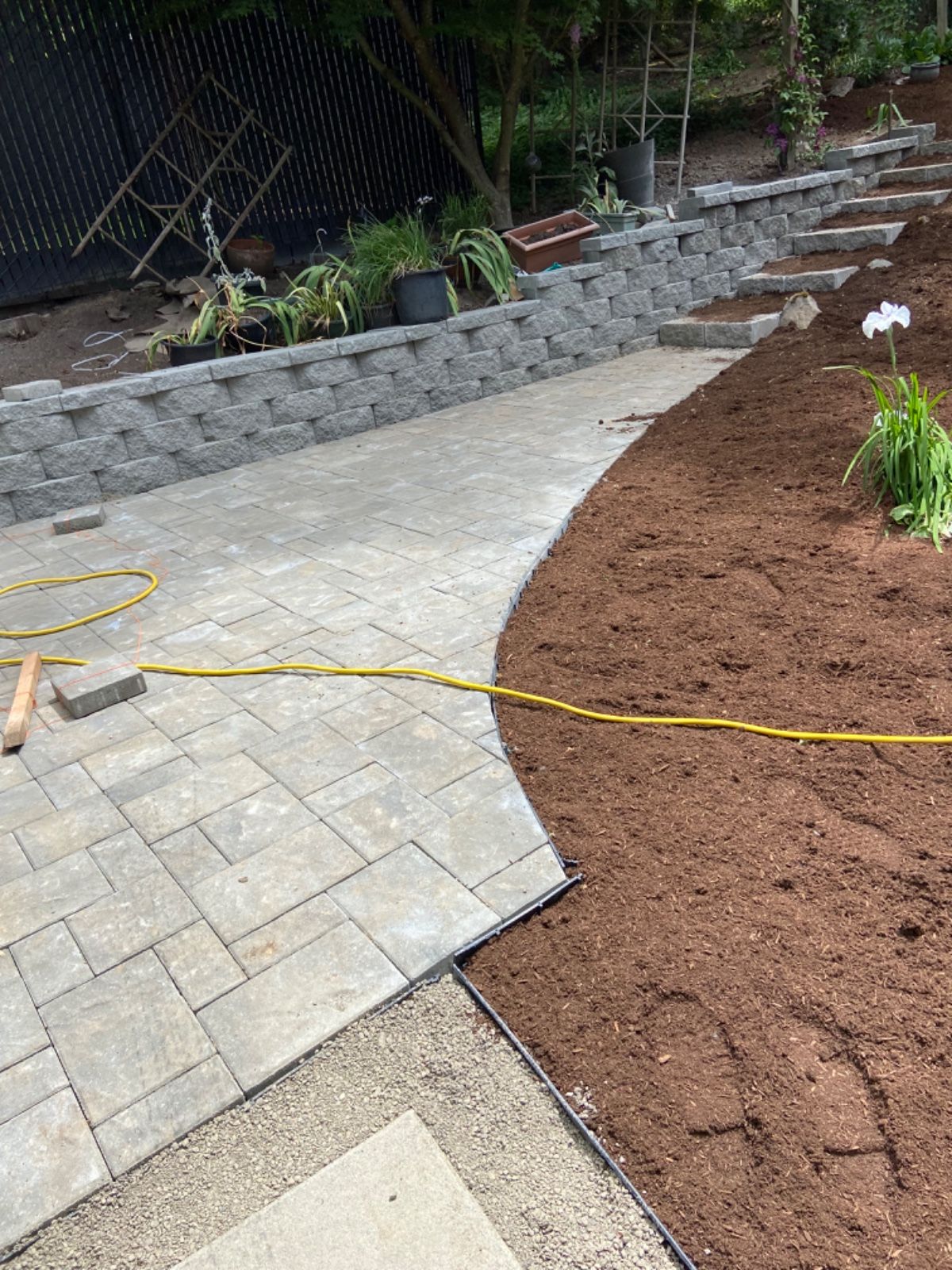 A patio is being built in a backyard with a hose attached to it.