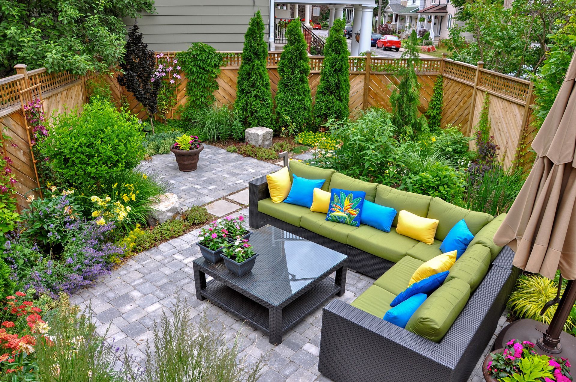 A patio with a sectional couch , coffee table , and umbrella.