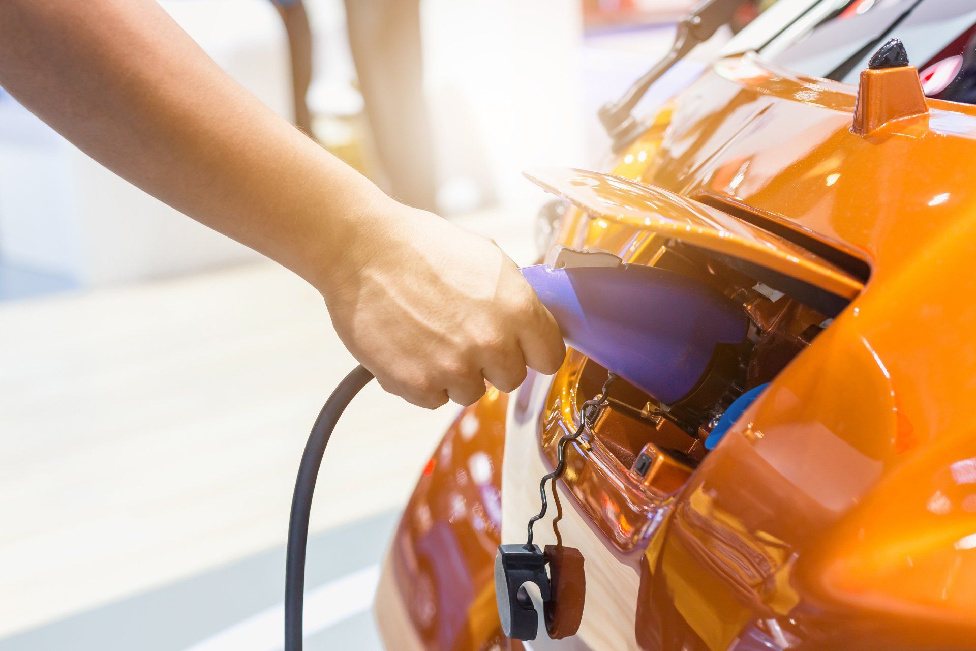 A person is charging an electric car in a parking lot.