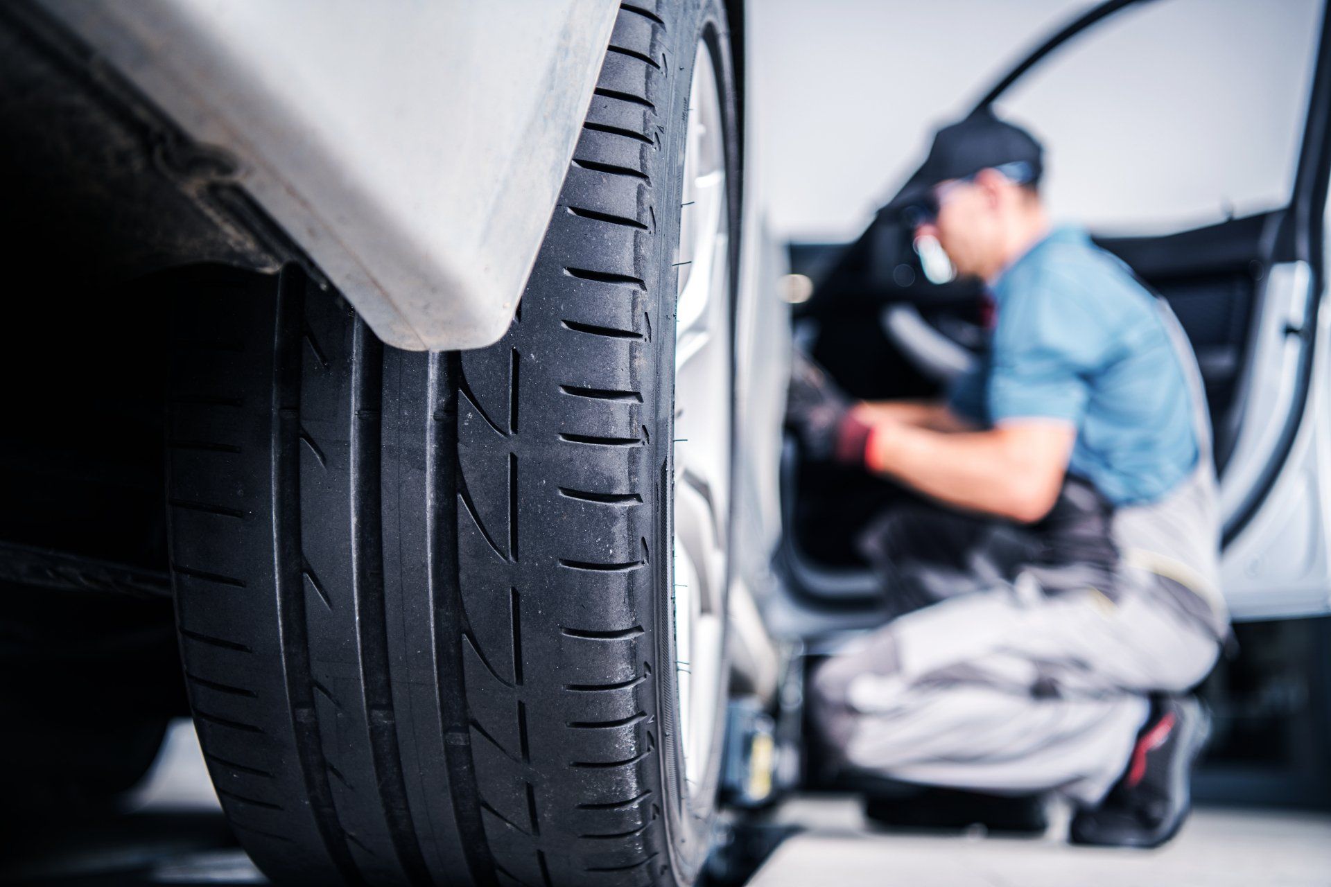 A man is working on a car tire in a garage.