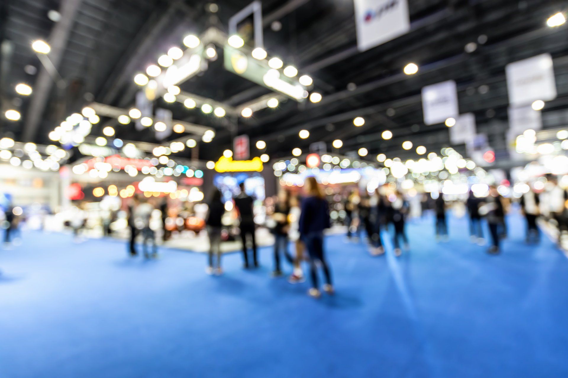 A blurry picture of a group of people standing in a room at a convention.