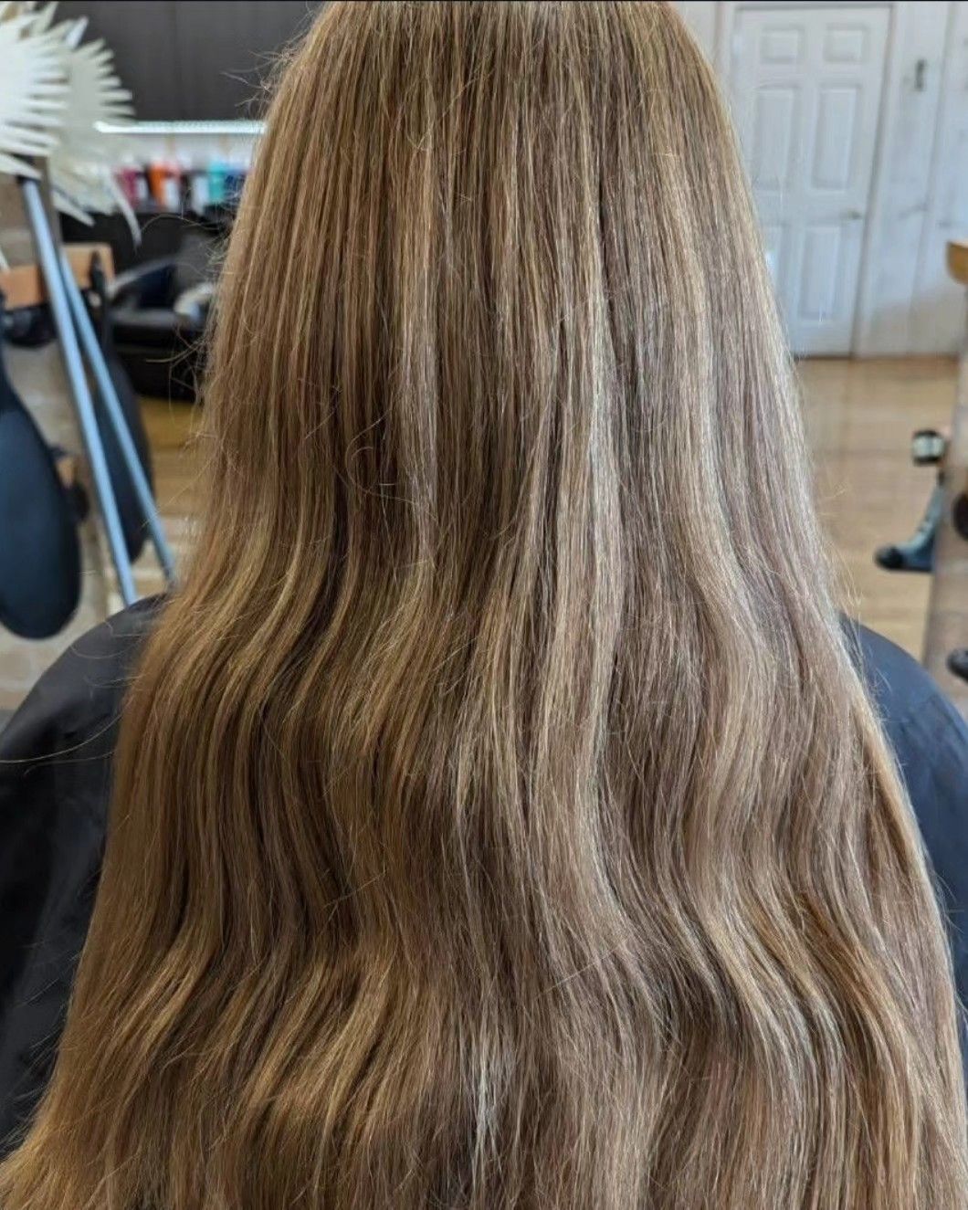 Back view of long, wavy light brown hair in a salon setting