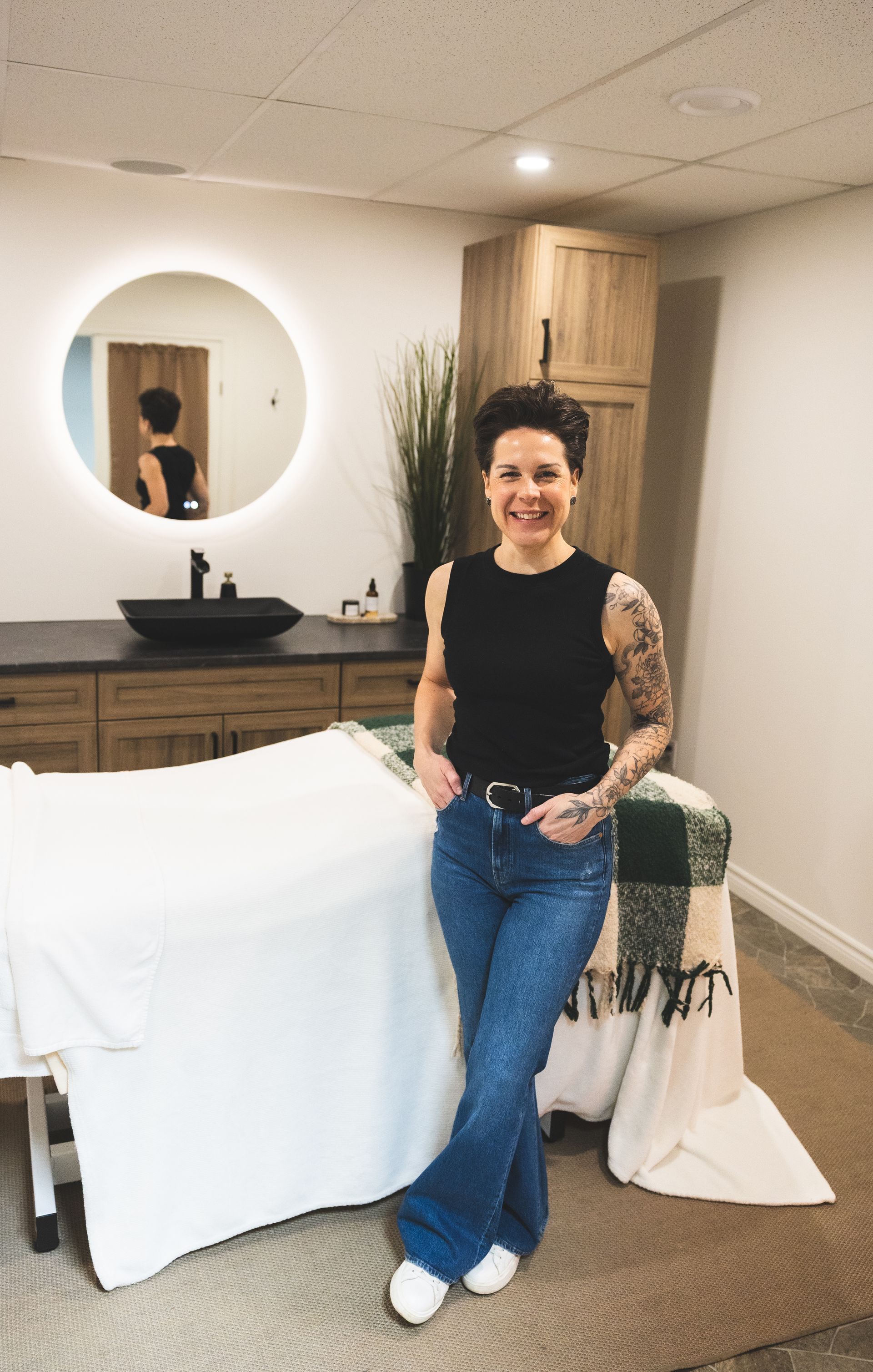 Michelle stands in a bright treatment room in front of a massage table.