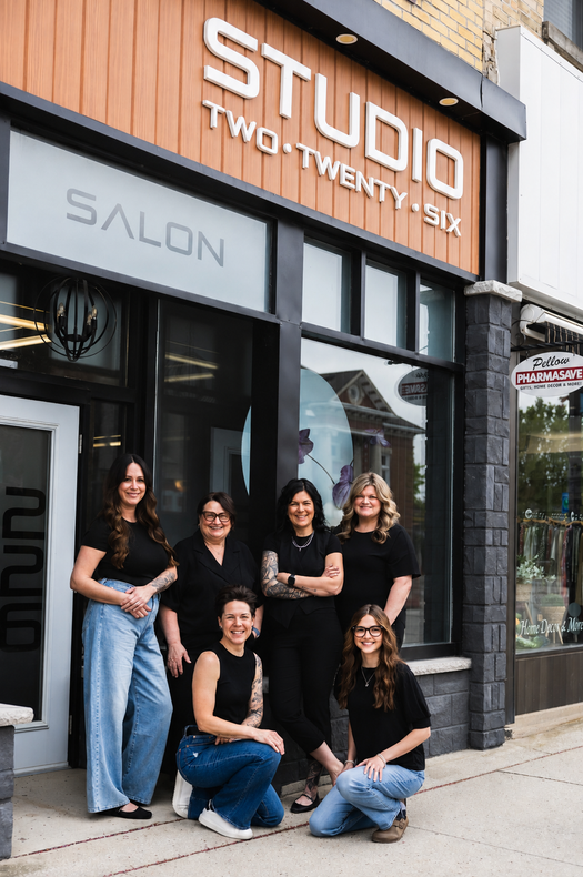 Six people posing outside Studio Two Twenty Six salon storefront