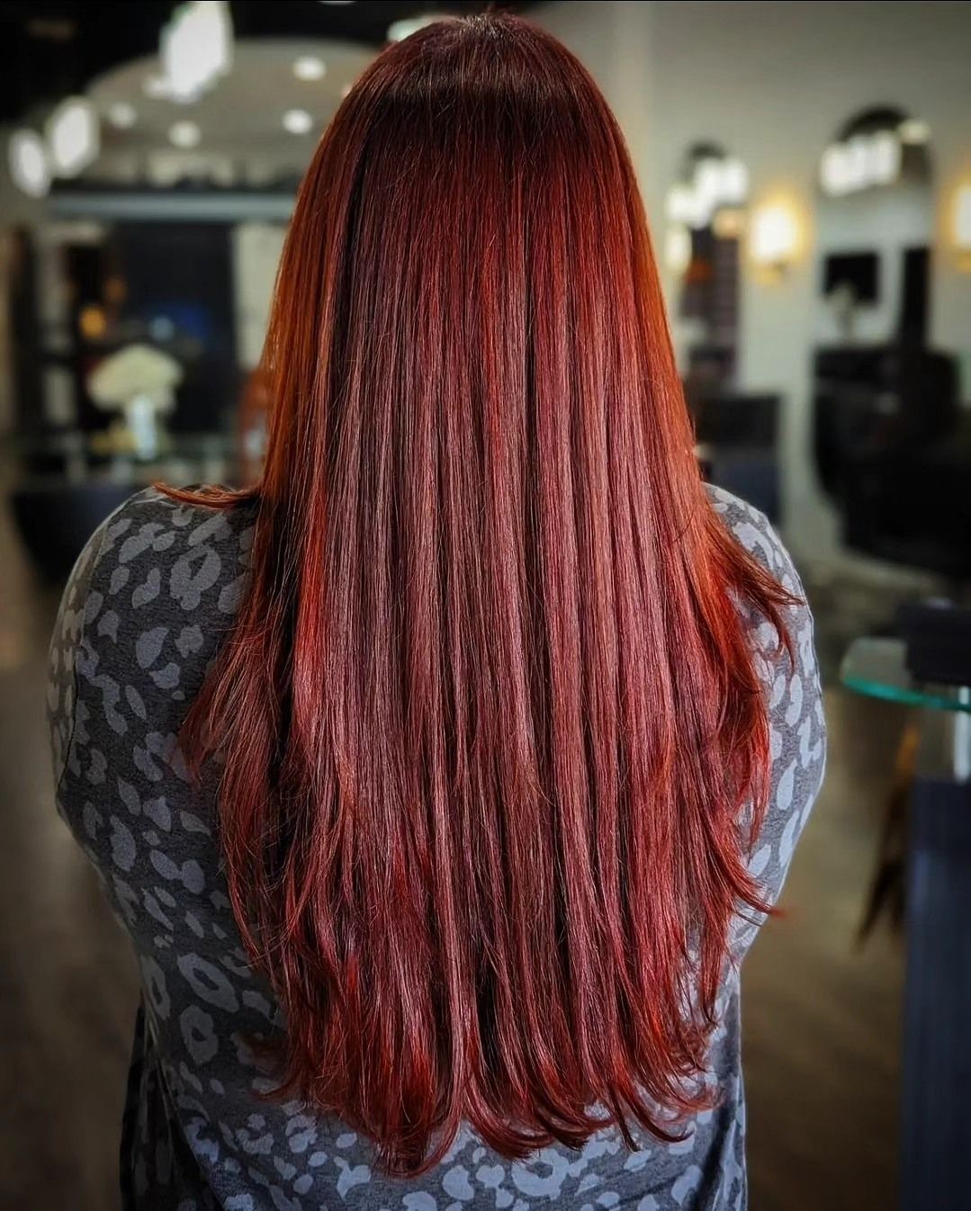 Back view of long, straight auburn-red hair in a salon setting