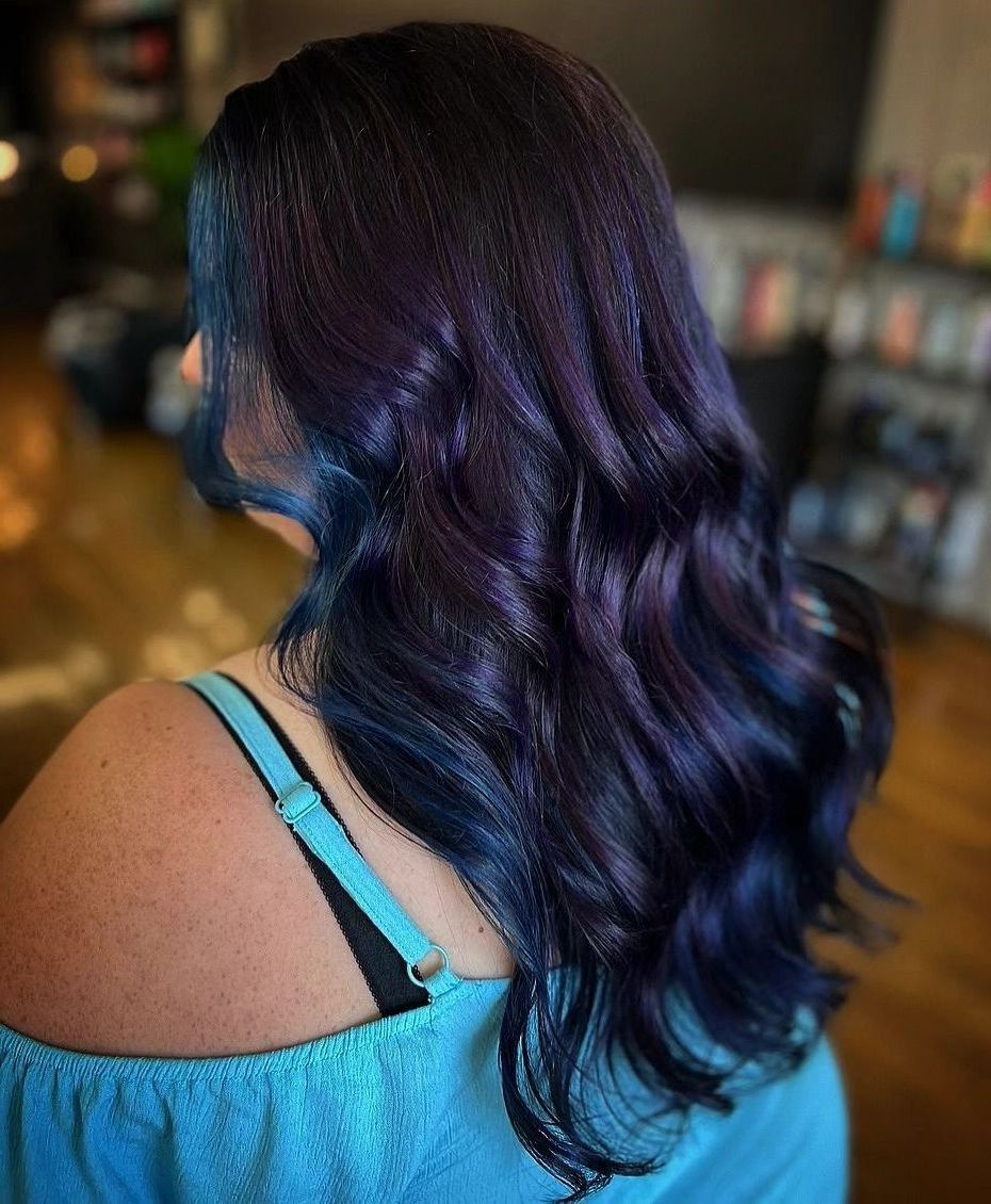 Back view of wavy dark purple hair with blue highlights