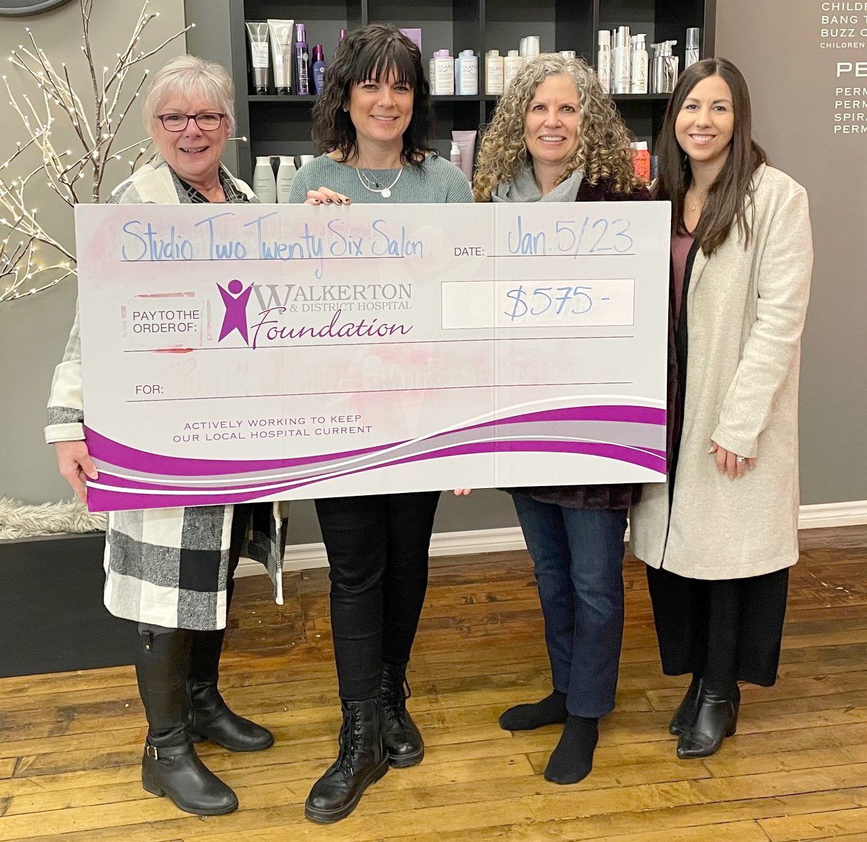 Four women holding a large donation check at a fundraising event inside Studio 226