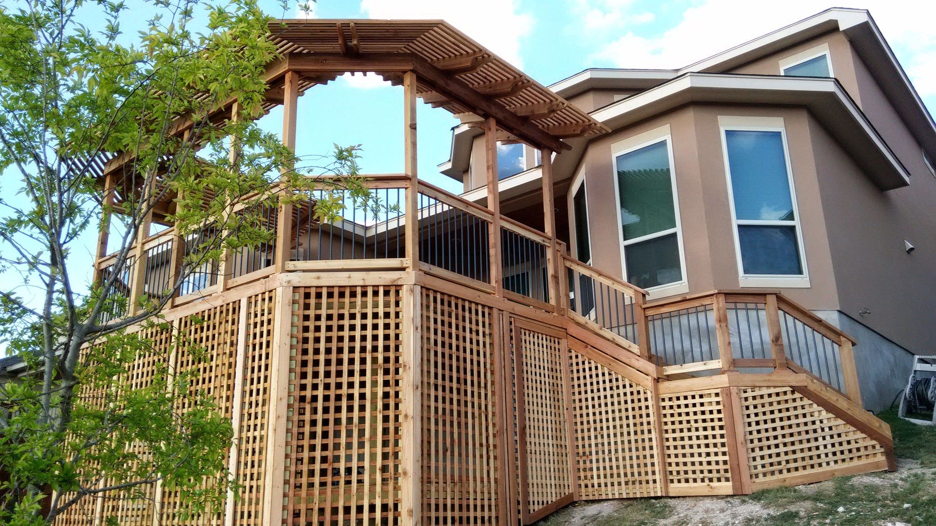 A wooden pergola is sitting under a blue sky in a backyard.
