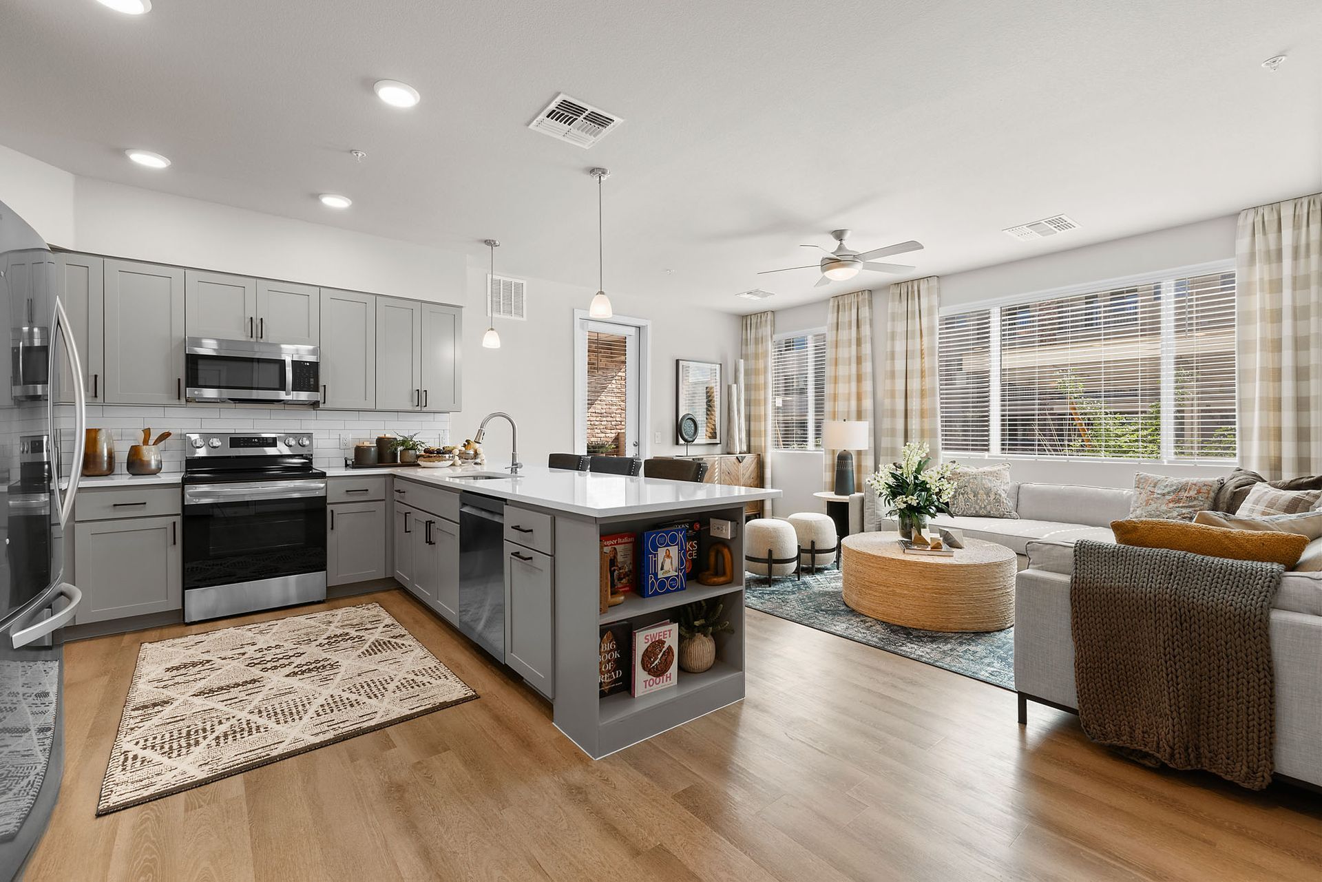 Modern kitchen and living room with gray cabinets, island, and large windows at Marq Bronco Butte, offers  apartments in North Phoenix, AZ.